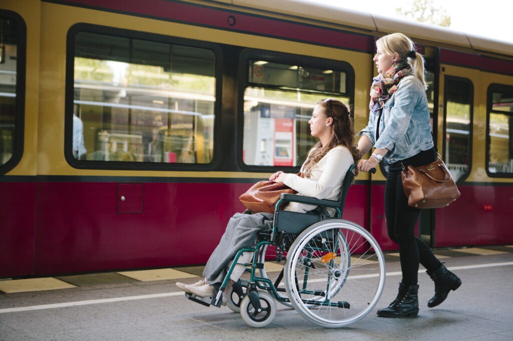 physically handicapped woman in wheelchair gets assistance disabled young woman in wheelchair at railroad track